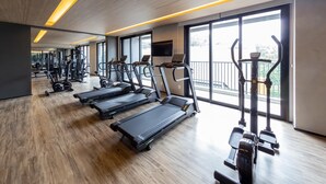 Une salle de sport moderne équipée de tapis de course, de vélos elliptiques et de matériel de musculation.