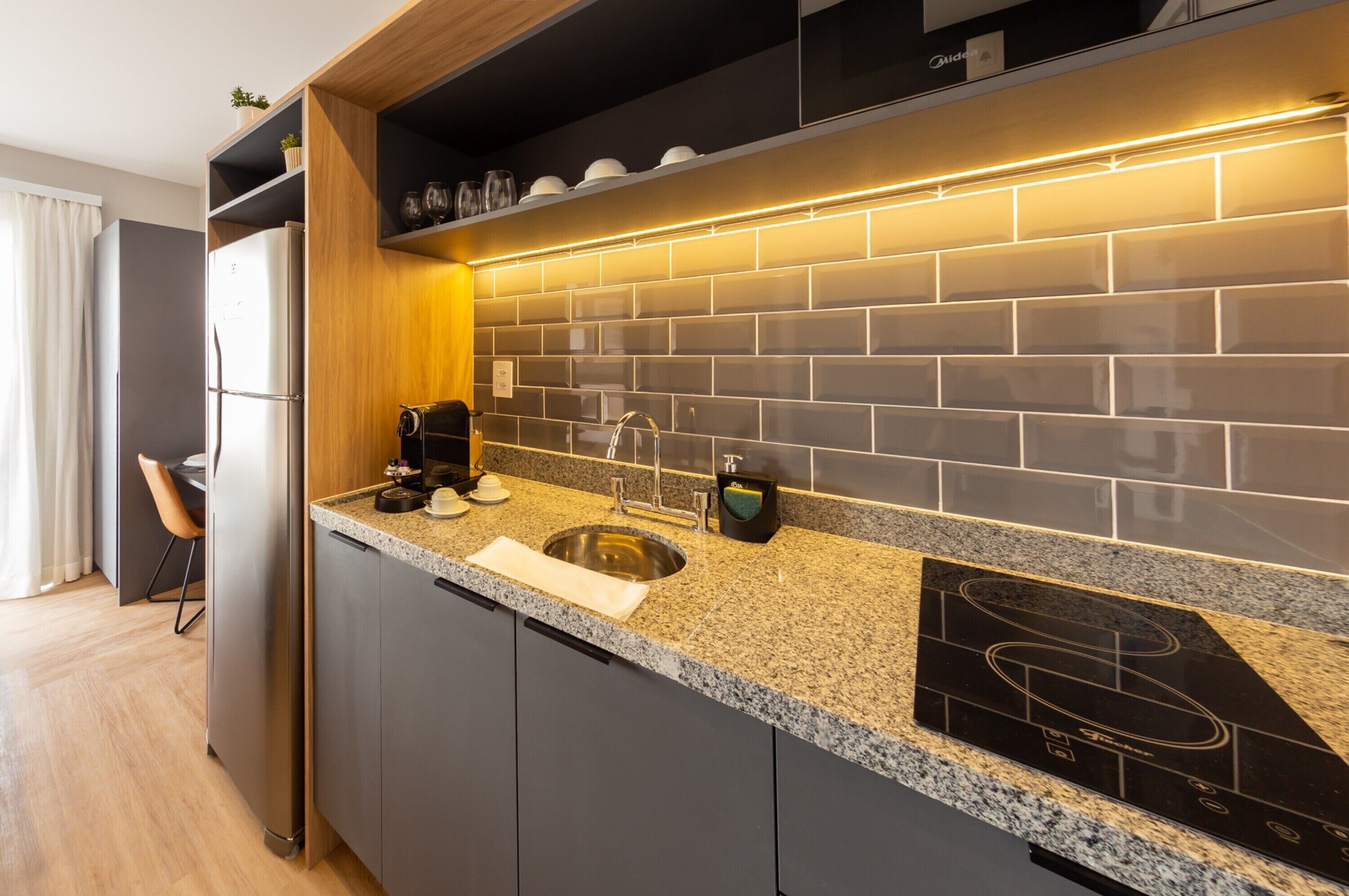 A modern kitchen with a built-in stove, a sink, and a countertop with a coffee maker.