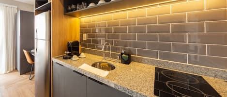 A modern kitchen with a built-in stove, a sink, and a countertop with a coffee maker.