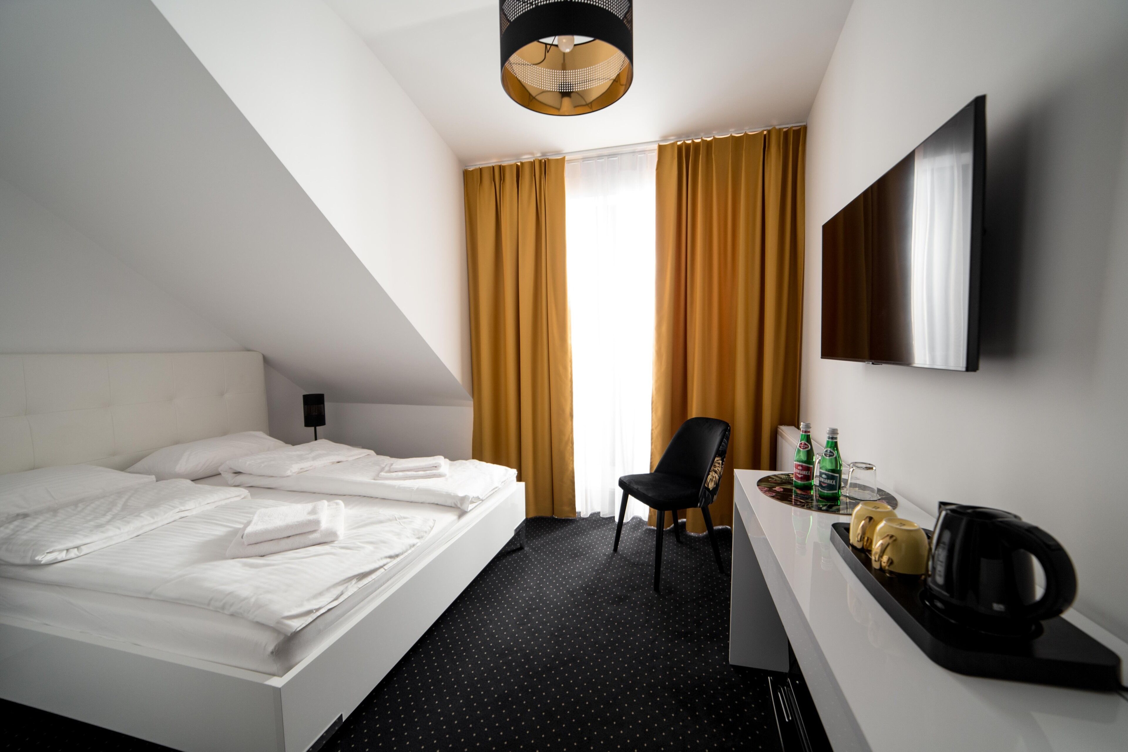 Een hotelkamer met een bed, een bureau met een stoel, een flatscreen-tv en een koffiezetapparaat.