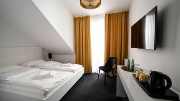 Een hotelkamer met een bed, een bureau met een stoel, een flatscreen-tv en een koffiezetapparaat.