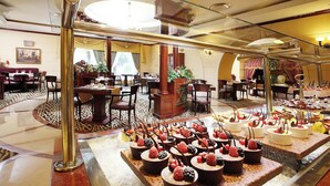 A hotel lobby with a central round table, multiple seating areas, and a dessert display. - Knight Castle Hotel  (Dubai)