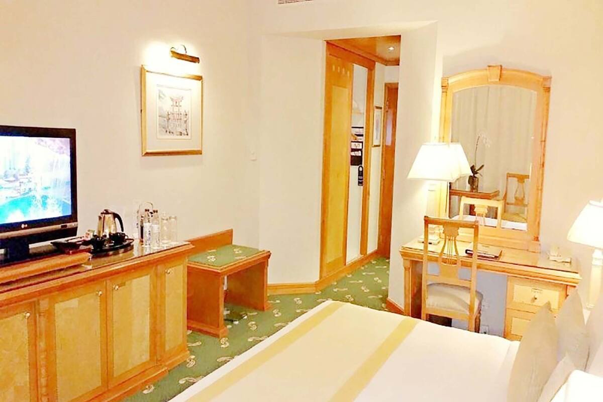 A hotel room with a bed, a desk, a television, and a mirror.
