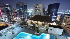 A rooftop pool area with lounge chairs and a bar, surrounded by high-rise buildings. - Knight Castle Hotel  (Dubai)