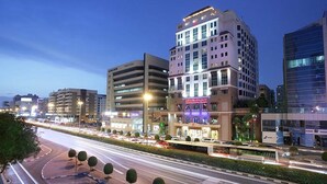 A multi-story hotel with a prominent sign, surrounded by other buildings and a busy road with light trails. - Knight Castle Hotel  (Dubai)