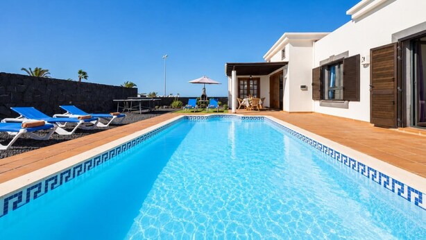 A swimming pool with lounge chairs, a table, and a view of the ocean. - Villa Capricho - Three Bedroom Villa, Sleeps 6 (Montaña Roja)