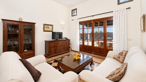 A living room with a sofa, a cabinet, a television, and a table with fruit. - Villa Capricho - Three Bedroom Villa, Sleeps 6 (Montaña Roja)