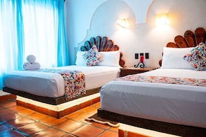 Habitación de hotel con dos camas, piso de baldosas y un cabecero decorativo.