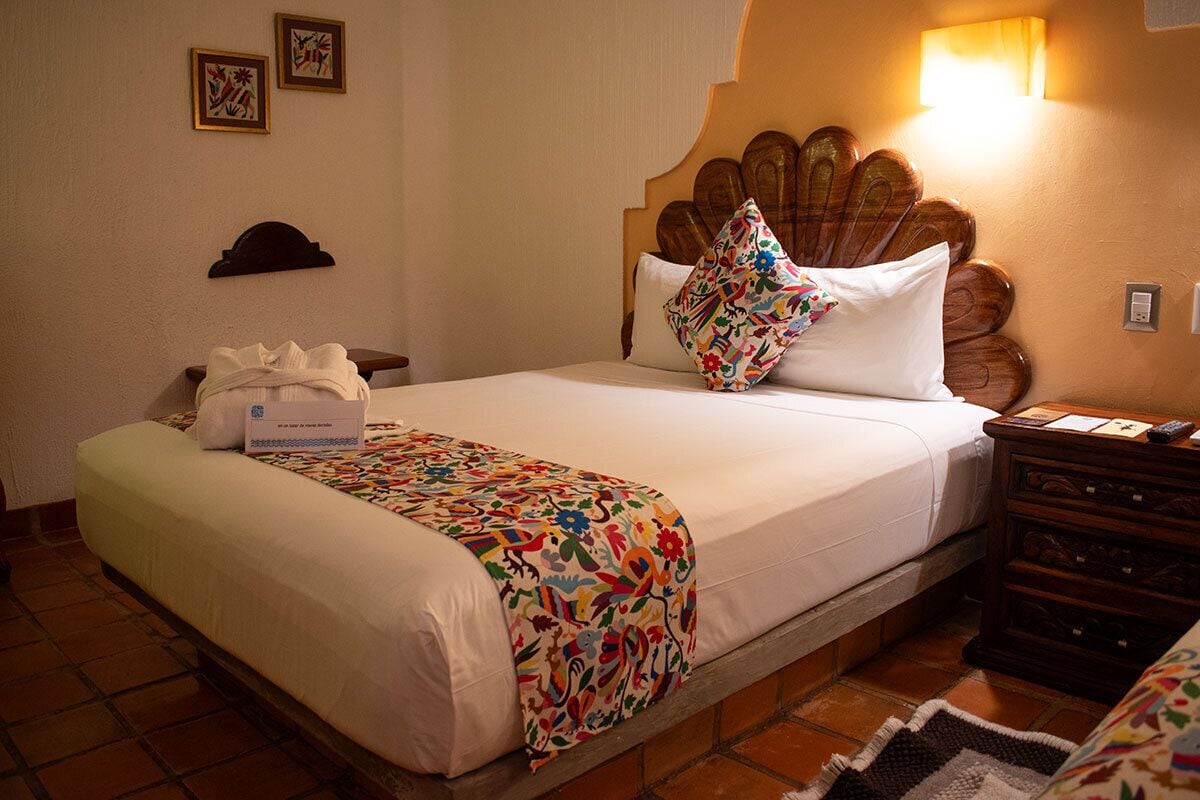 Ein Hotelzimmer mit einem Bett, einem Nachttisch, einer Wandleuchte und zwei gerahmten Bildern.