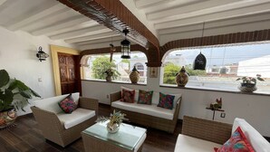 Una sala acogedora con muebles de mimbre, una mesa de centro de vidrio y cojines decorativos.