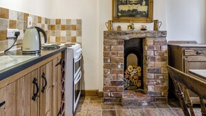 A kitchen with a stove, kettle, and a fireplace with a painting above it. - Shepherds Hut - UK45529 (Leighton, near Shrewsbury)