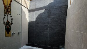 A modern bathroom with a glass-enclosed shower, a large bathtub, and a stone-tiled shower area. - Refugio en el Bosque (Envigado)