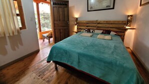 A bedroom with a wooden bed, a map on the wall, and a door leading to an outdoor area. - Refugio en el Bosque (Envigado)