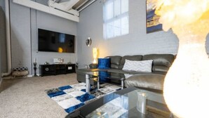 A modern living room with a large flat-screen TV, a leather sofa, and a coffee table.