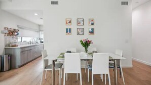 A modern dining area with a white table, four chairs, and a vase of flowers. - Close to Hollywood and Getty with a Panorama Deck (Los Angeles)