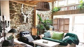 A cozy living room with a stone wall, leather armchair, green sofa, and a coffee table.