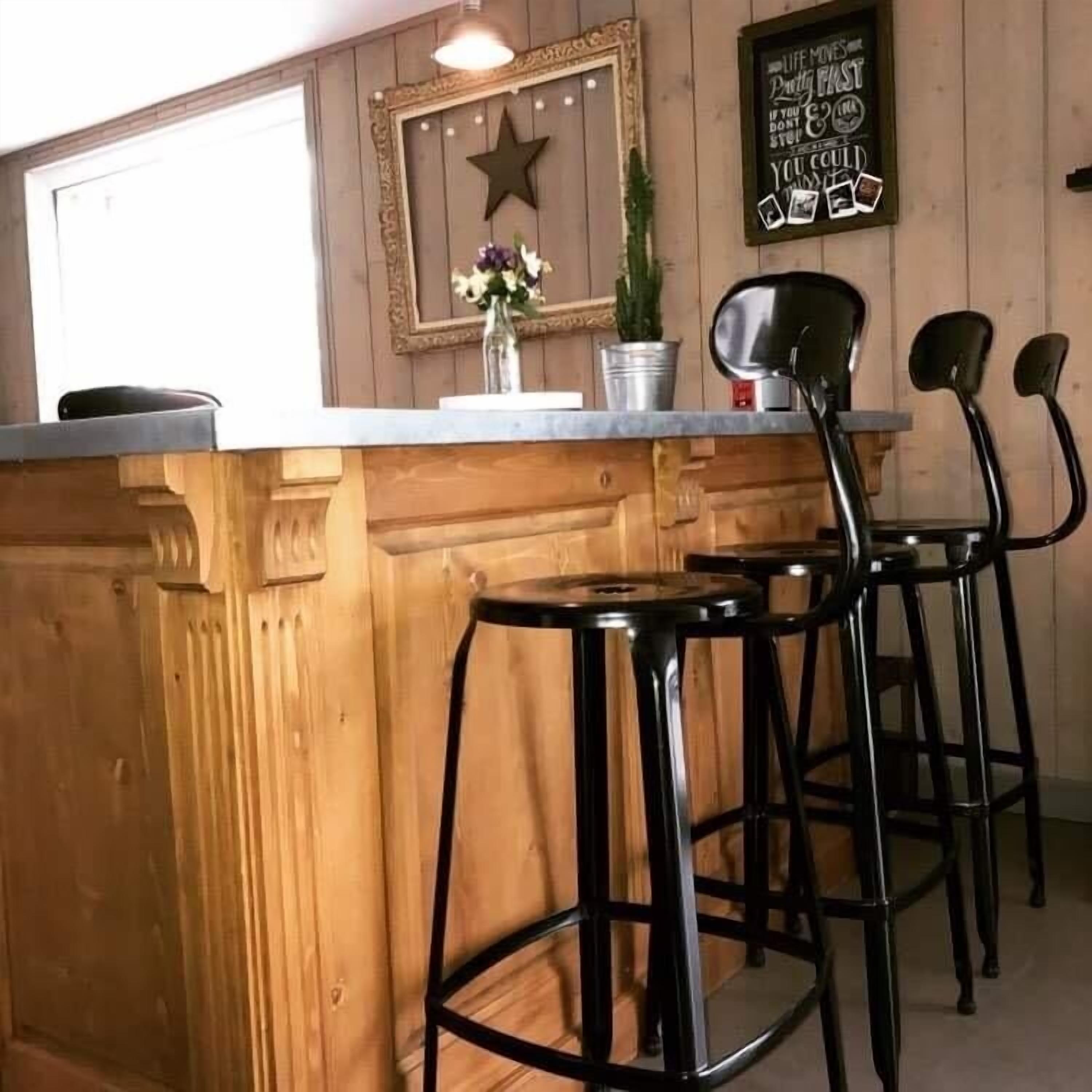 Angolo bar con rivestimenti in legno, decorazione a stella, un quadro incorniciato e un cartello con un messaggio.