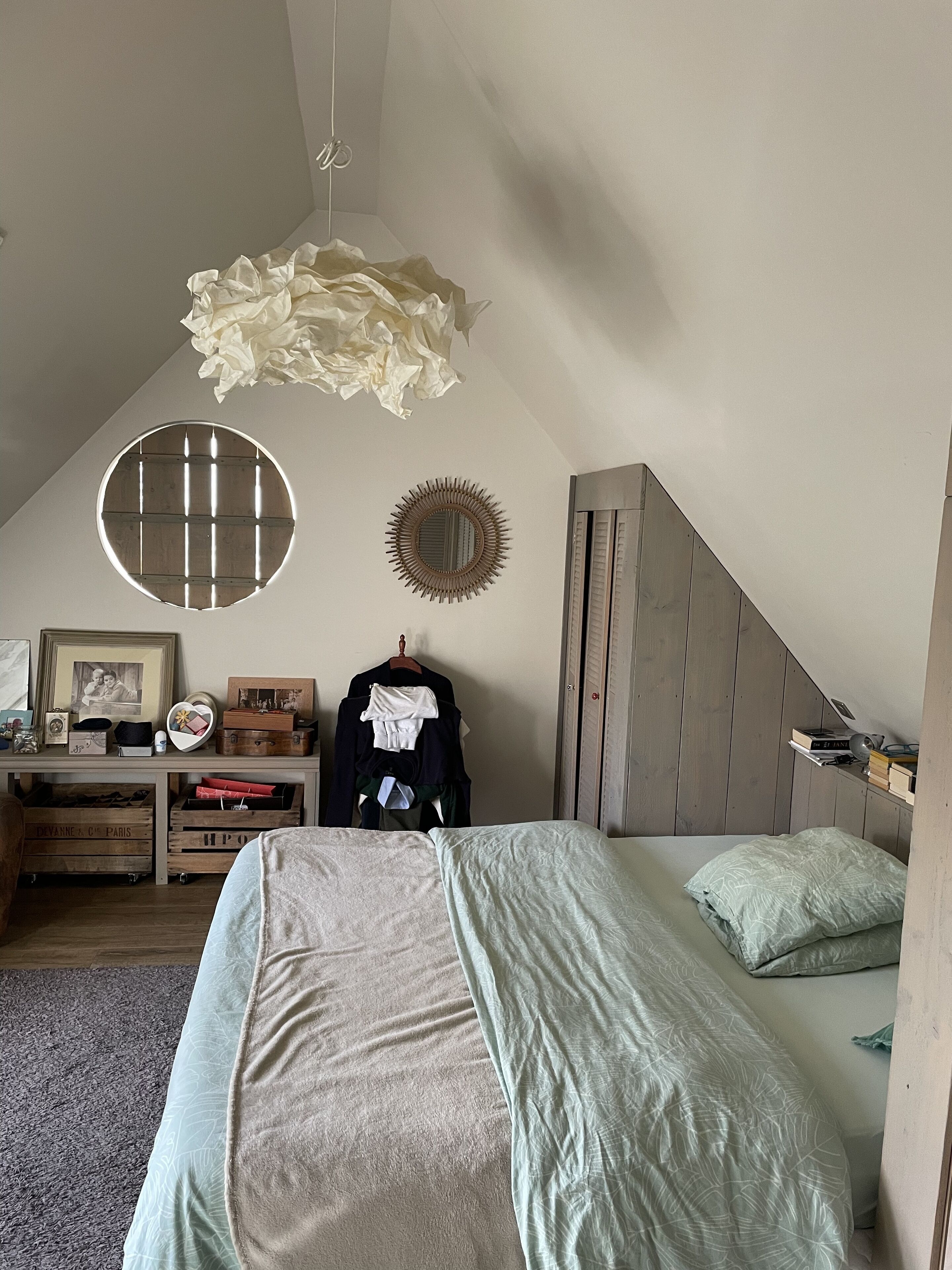 Une chambre à coucher comprenant un lit, une commode, un miroir et un luminaire suspendu.