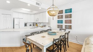 Una cucina moderna con mobili bianchi, un'isola centrale e un'area pranzo con tavolo e sedie in legno.
