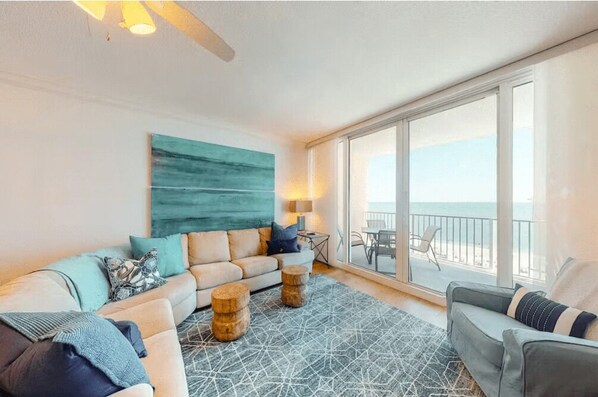 Relax in this ocean-view living room with a sofa, armchair, and patterned rug.