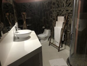 Bathroom features a stone wall, bowl sink, and glass shower enclosure.