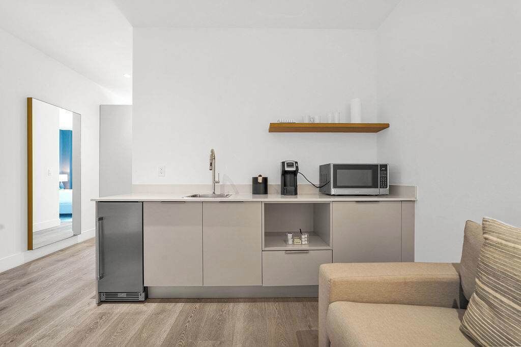A compact kitchen with a microwave, coffee maker, and a small shelf.