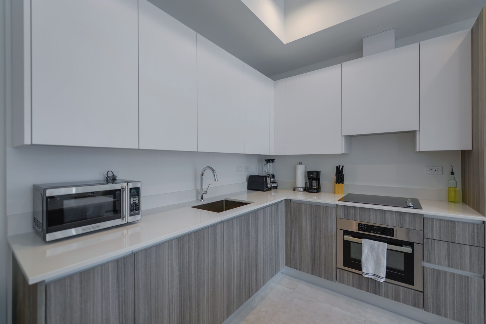 A modern kitchen with white cabinets, a microwave, a toaster, a coffee maker, and an oven.