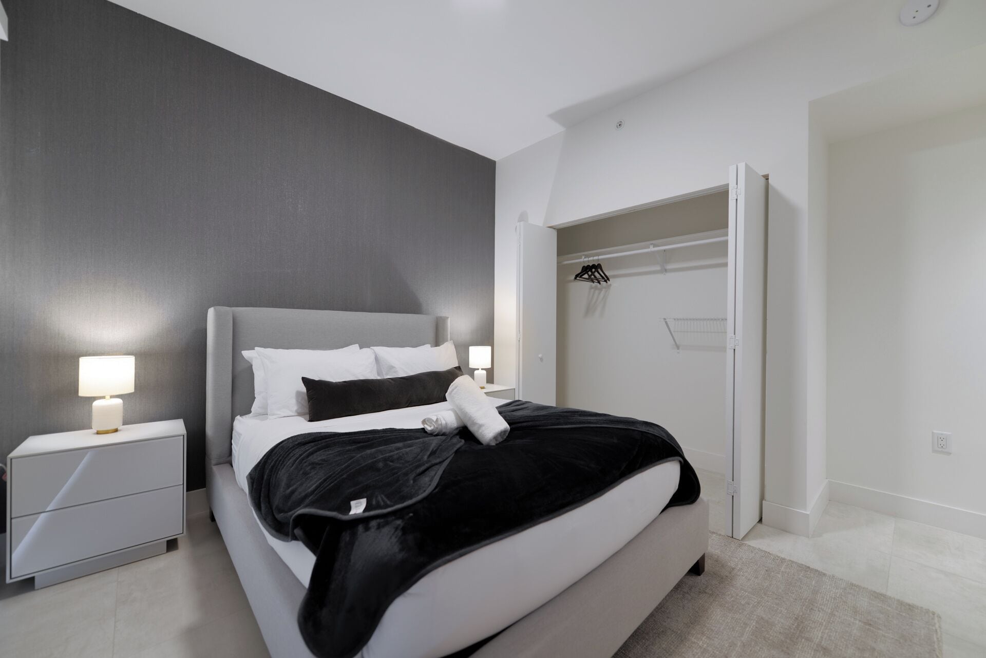 Une chambre moderne avec un lit, des tables de chevet et un dressing.