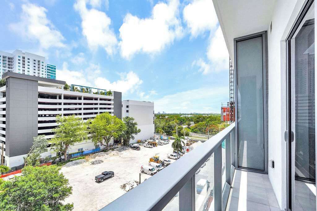 A balcony with a view of a parking garage and surrounding buildings.