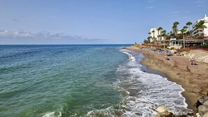 A beach with a hotel on the right, featuring palm trees and a clear sky. - SR Almirante 1ª Linea de Playa (Mijas)