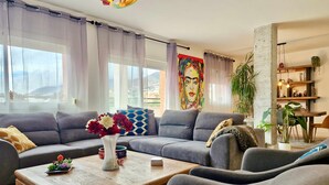 A modern living room with a grey sectional sofa, a wooden coffee table, and a vibrant abstract painting on the wall. - SR Penthouse Parque Olivar Torremolinos (Torremolinos)