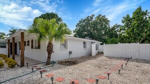 A white building with a covered porch, a palm tree, and a gravel path with red tiles. - Tampa's Hidden Gem - 1BR/1BA Guest Suite (Tampa)