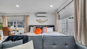 A modern hotel room with a large bed, grey upholstered sofa, and a desk with a chair. - Tampa's Hidden Gem - 1BR/1BA Guest Suite (Tampa)
