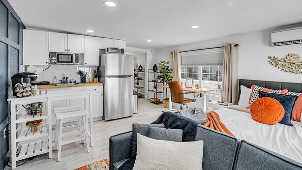 A modern apartment with a kitchenette, a dining area, and a bedroom with a large bed and multiple pillows. - Tampa's Hidden Gem - 1BR/1BA Guest Suite (Tampa)