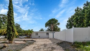 A house with a gravel driveway, a white fence, and a guest parking sign. - Tampa's Hidden Gem - 1BR/1BA Guest Suite (Tampa)