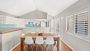 A modern kitchen with white cabinets, a blue countertop, and a wooden dining table with four chairs.