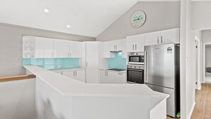 A modern kitchen with white cabinets, a stainless steel refrigerator, a microwave, and an oven.