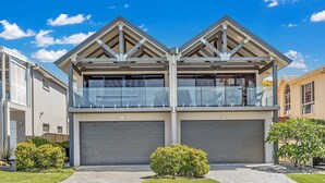 A modern two-story house with a garage, a balcony, and a well-maintained garden.