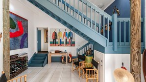 A spacious living area with a staircase, a wine rack, and a painting of abstract figures. - Shoal Bay Riggers - 7  Rigney St, Shoal Bay (Shoal Bay)