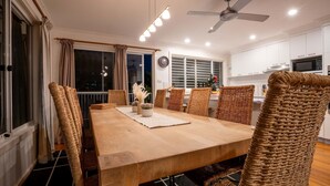 A dining area with a wooden table, wicker chairs, and a ceiling fan. - Shoal Bay Riggers - 7  Rigney St, Shoal Bay (Shoal Bay)