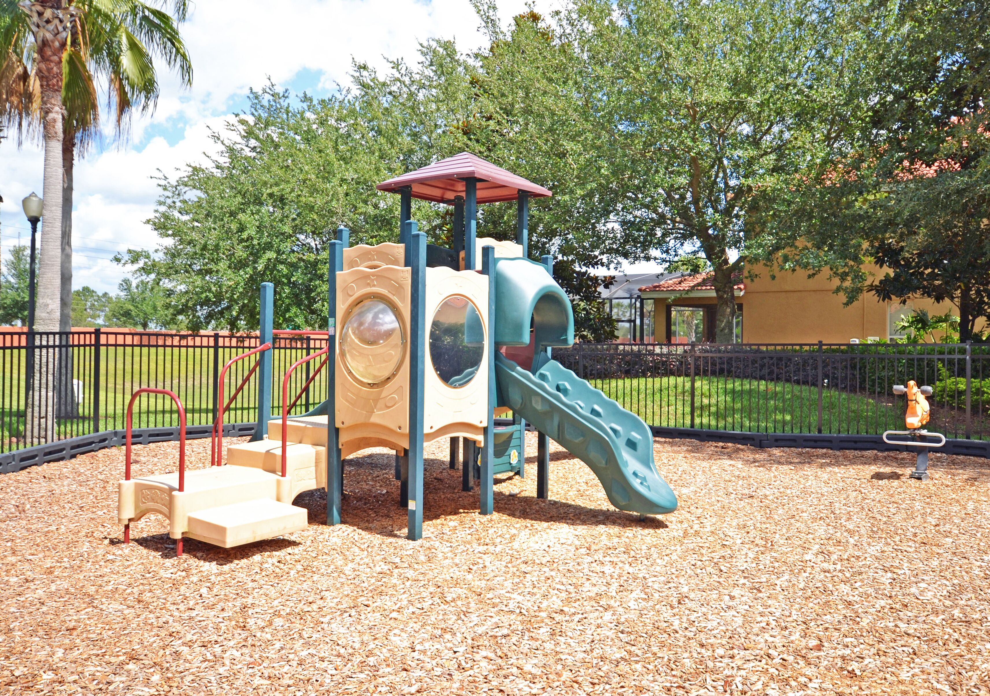 Un parque infantil con tobogán, escaleras de acceso y una estructura de juego cubierta.