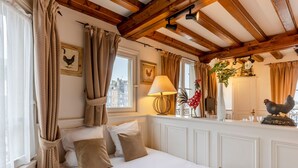 A cozy room with a bed, a window with curtains, a lamp, and a rooster decoration. - Key West - charming studio ON the port of Honfleur - Superb 360° view (Honfleur)