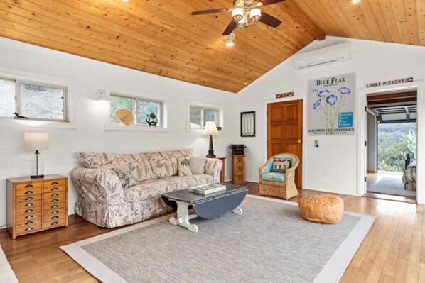A cozy living room with a wooden ceiling, a sofa, a coffee table, a lamp, a cabinet, and a rug.