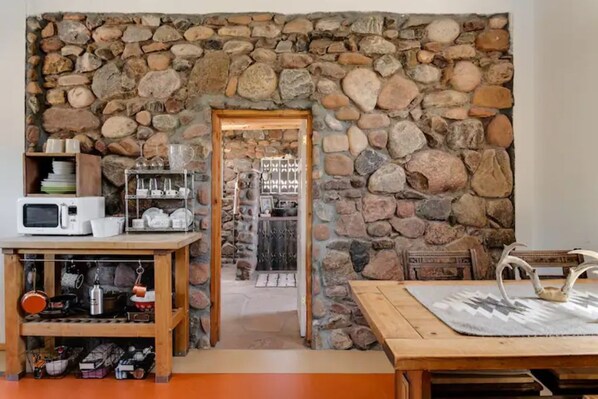 A stone wall interior with a wooden table and shelves. - La Biblioteca: Eclectic Cottage in OKeeffe Country (Abiquiu)