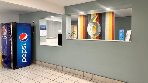 A reception area with a Pepsi vending machine, a number '6' sign, and a small plant. - Motel 6 Borger, TX – Boom Town (Borger)
