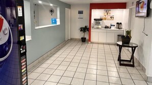 A hotel lobby with a vending machine, a small table with a plant, a coffee machine, and a TV on the wall. - Motel 6 Borger, TX – Boom Town (Borger)