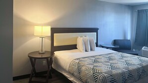 A hotel room with a bed, a bedside lamp, a chair, and a desk. - Motel 6 Borger, TX – Boom Town (Borger)