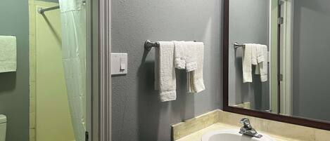 A bathroom with a bathtub, a sink, and a mirror.