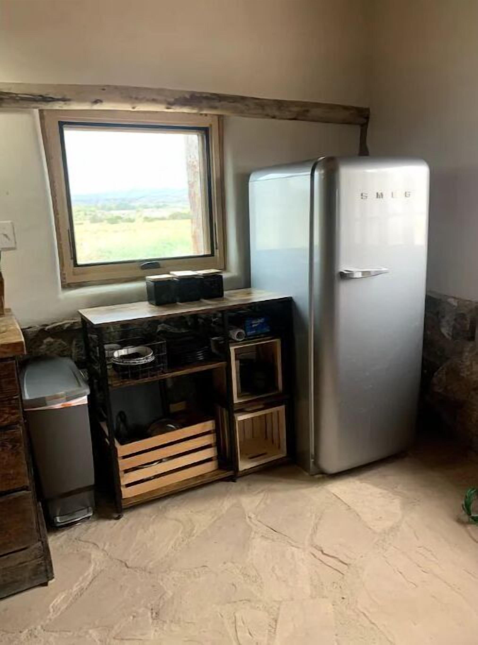 Una cocina compacta con refrigerador integrado, una ventana con vistas al exterior y un mostrador pequeño con alacenas.
