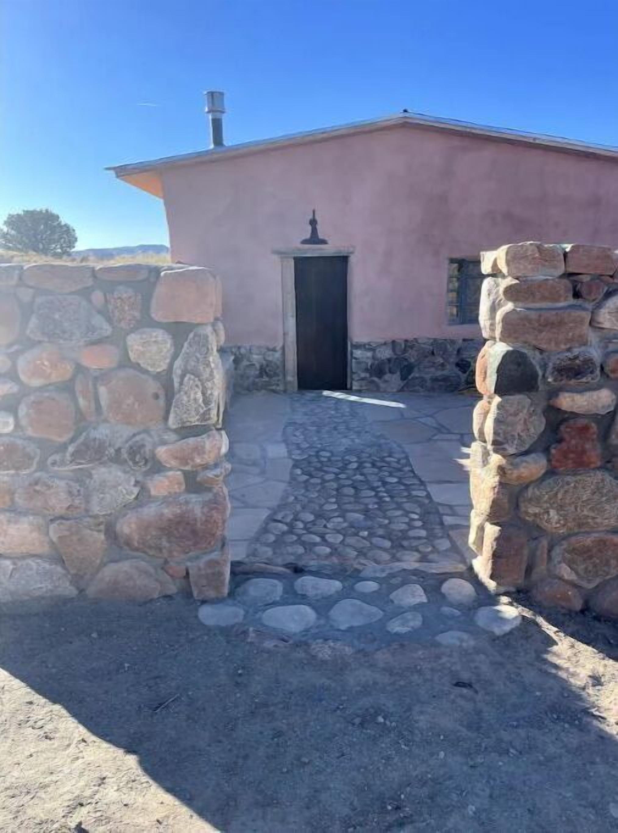 A building with a stone pathway leading to a door, surrounded by stone walls.